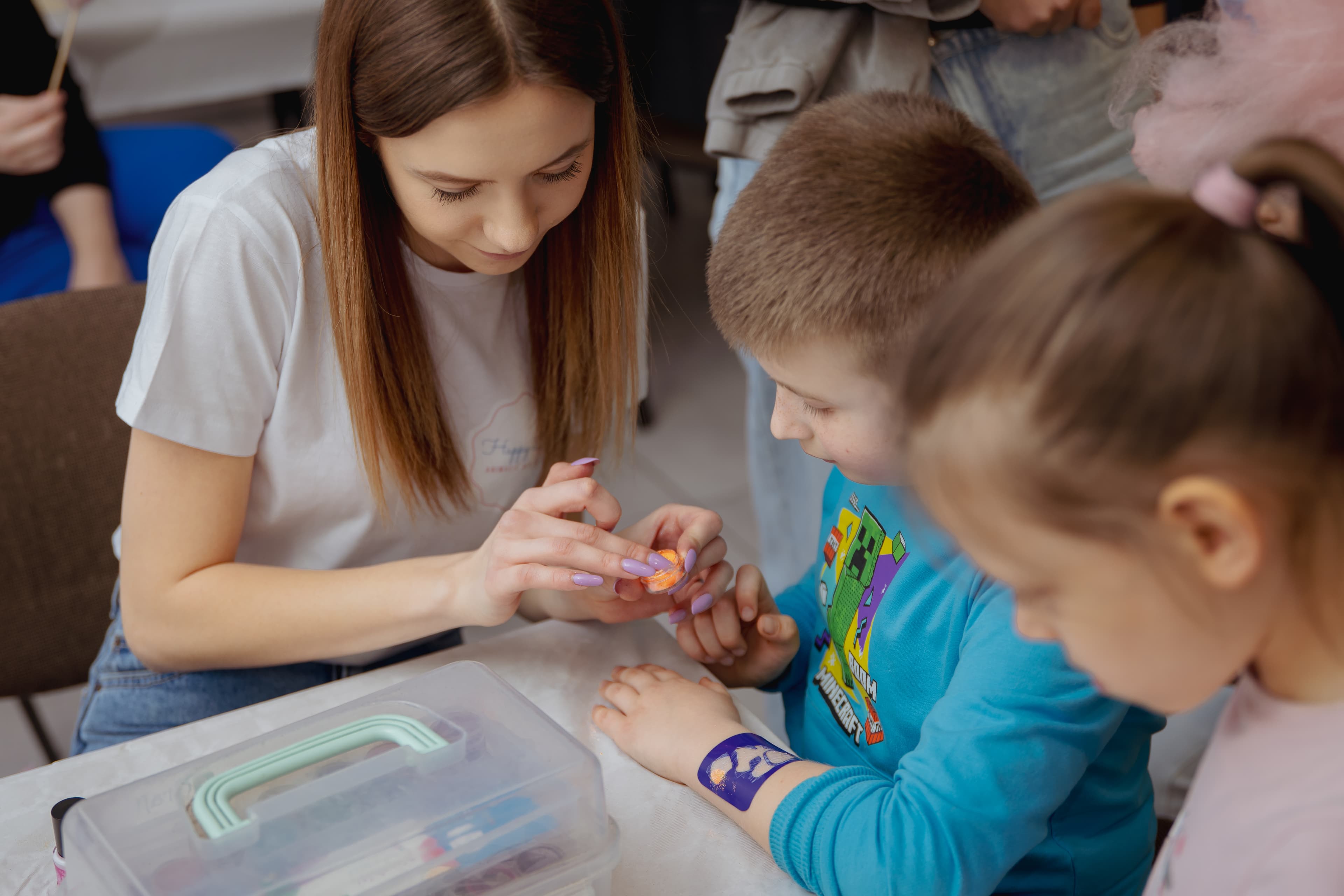 Animatorka wykonująca brokatowy tatuaż dziecku