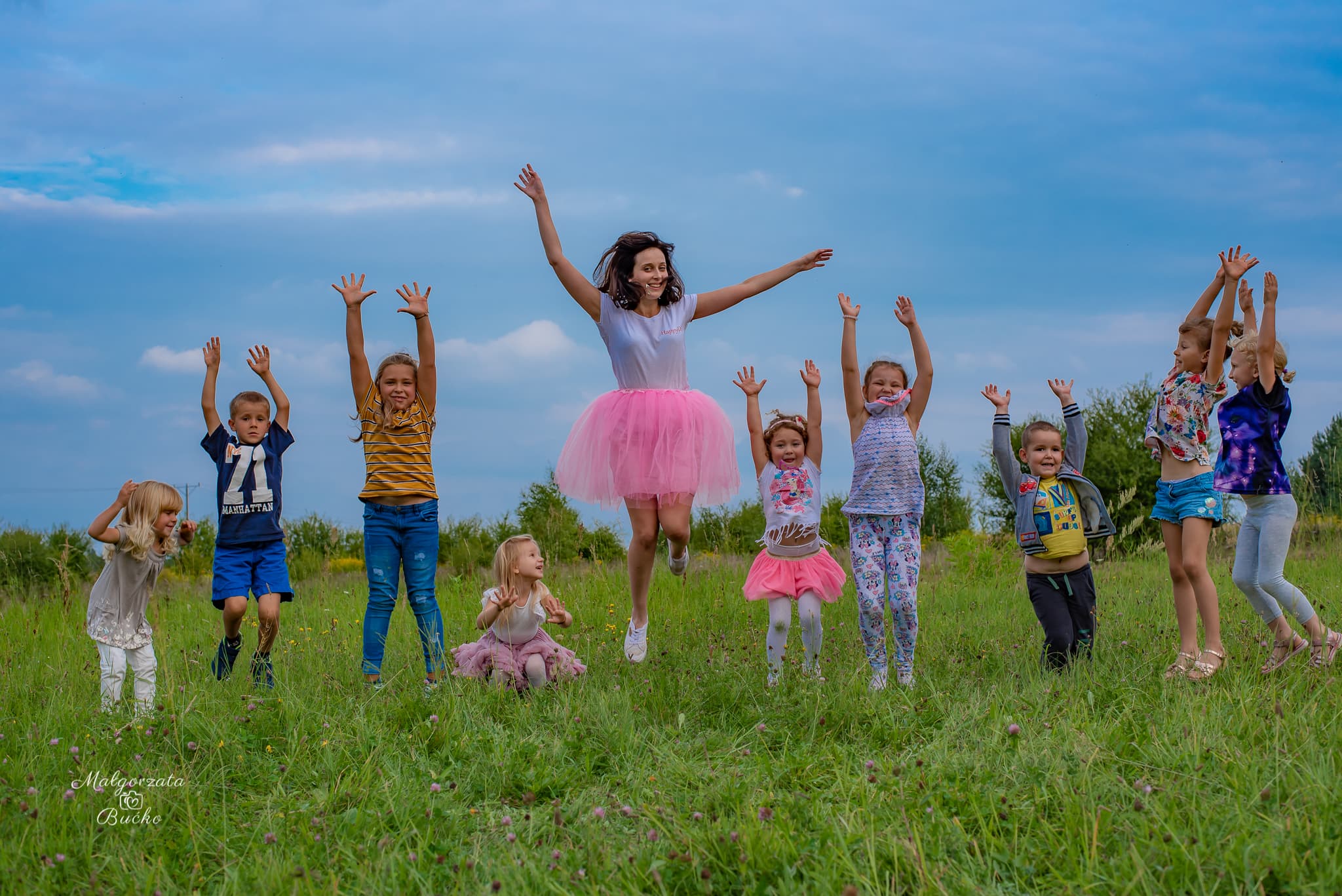 Animatorka prowadząca aktywną zabawę z grupą dzieci podczas wydarzenia plenerowego
